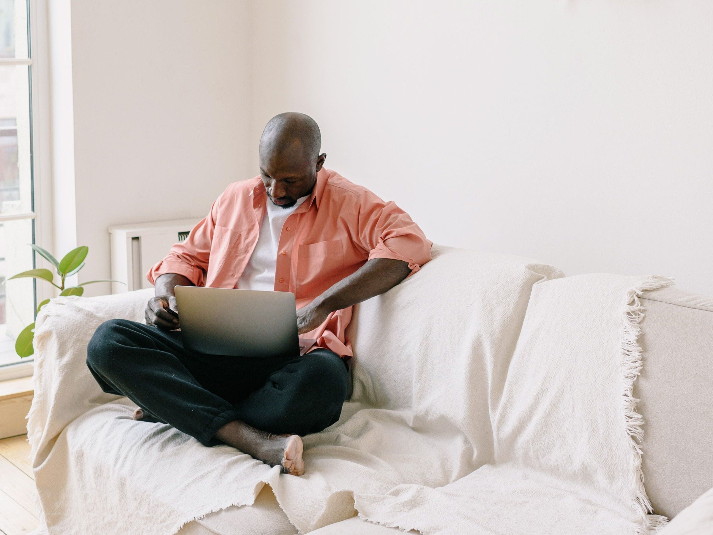 Man using a laptop on a sofa at home
